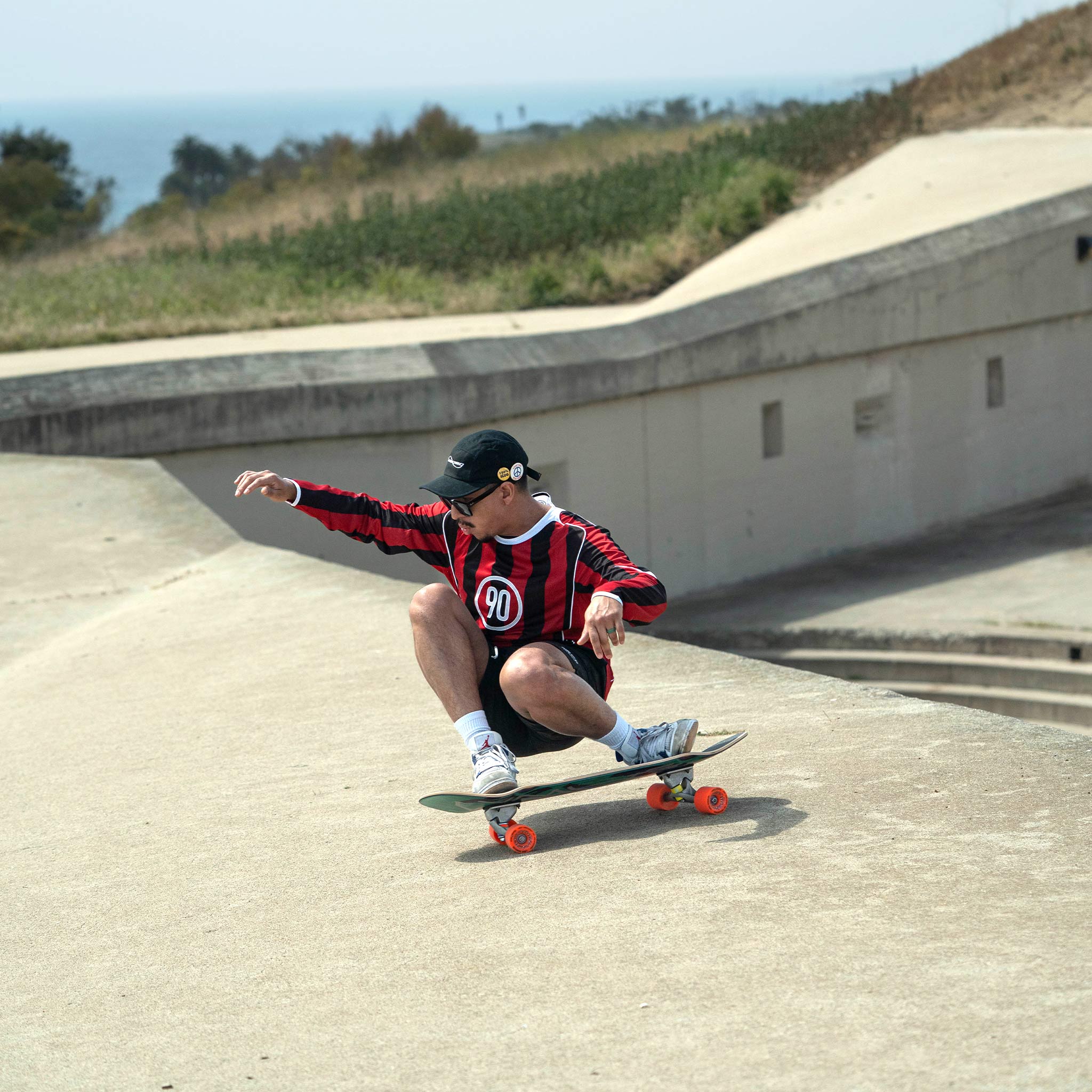 Person skateboarding at a concrete skate park with ocean view