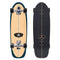 Top and bottom views of a Carver 30-Year Limited Edition surfskate skateboard on a white background. The bottom features a natural wood grain finish with a dark teal outline, while the top is covered in black grip tape with a center stripe cut out.