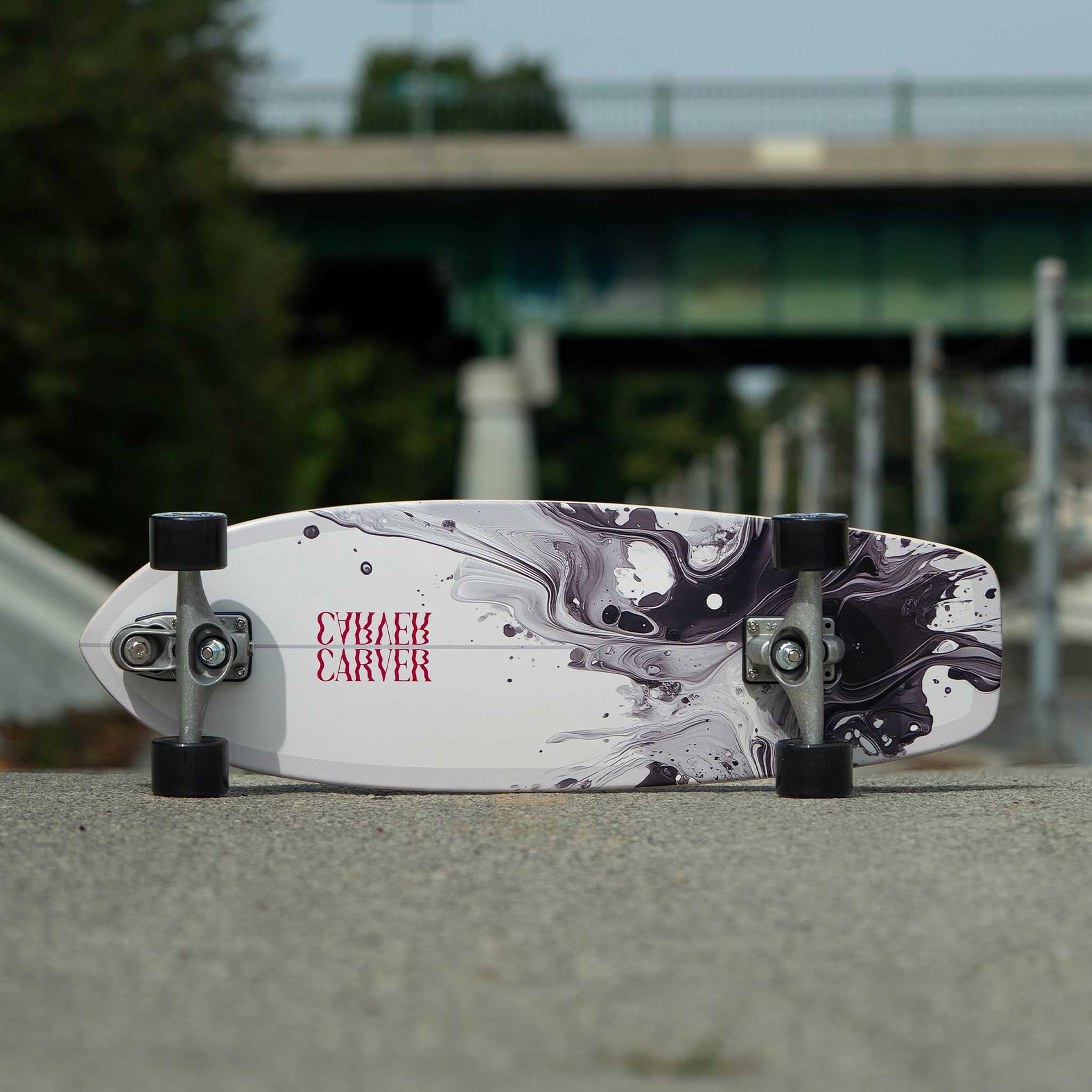 Marbled design skateboard on a concrete surface with blurred background