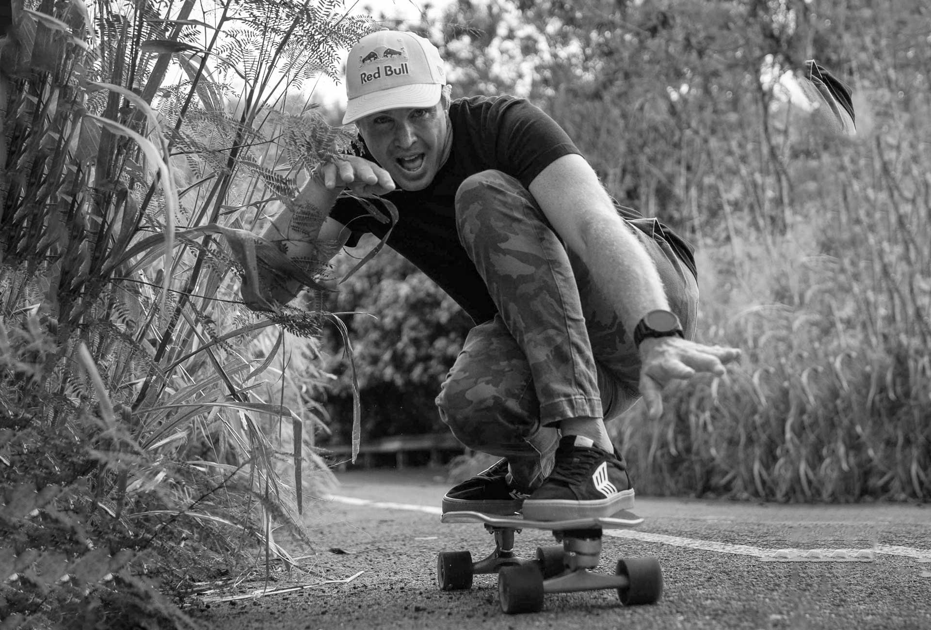Carver team rider Jamie O'Brien skateboarding outdoors with a cap and casual attire