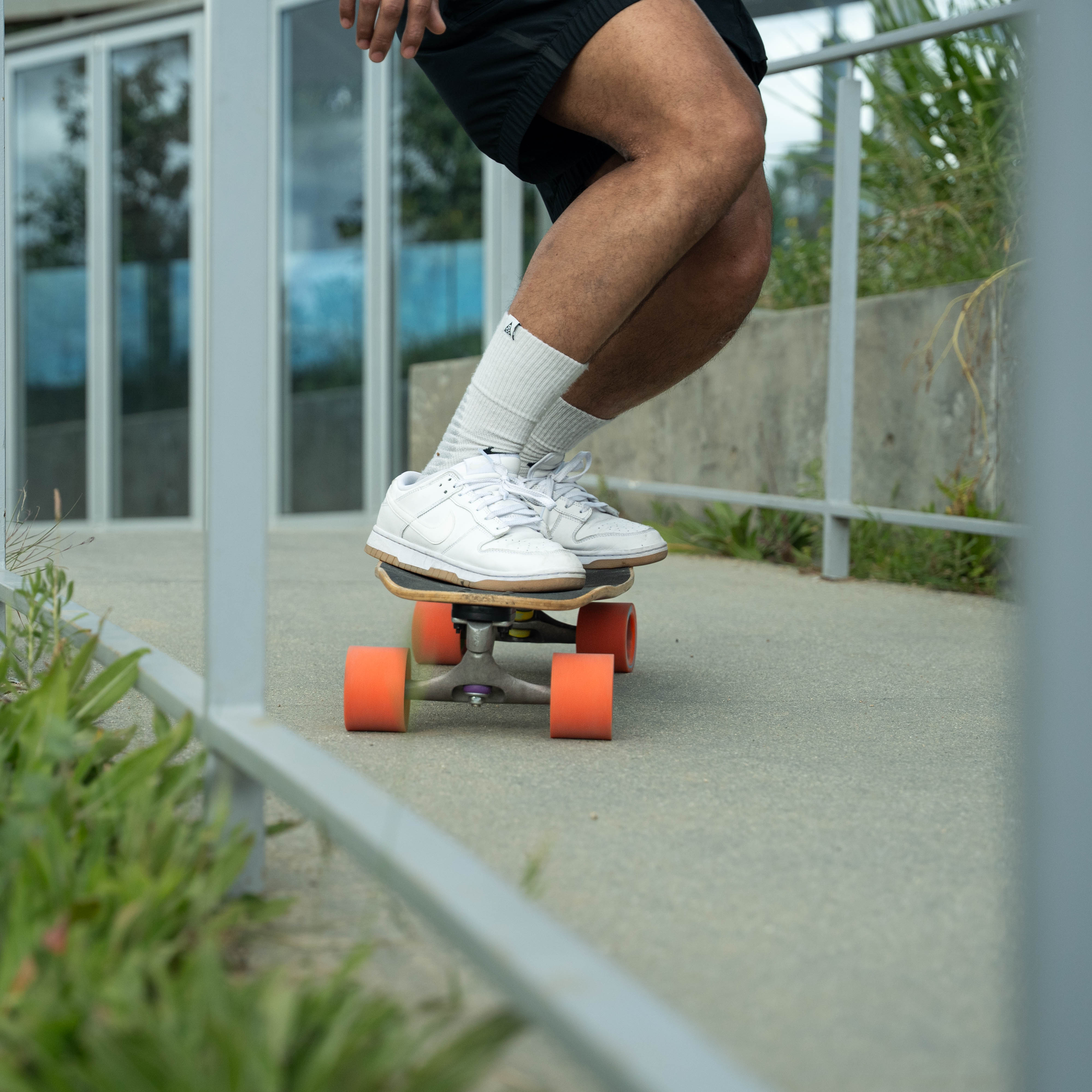 Person skateboarding on a concrete surface with greenery in the background